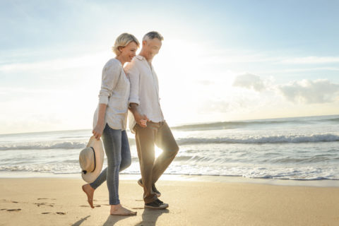 Mature couple walking on the beach at sunrise