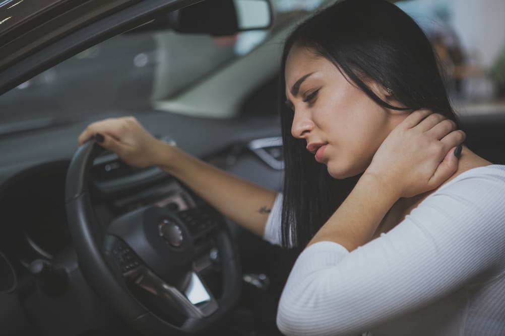 The girl suffering from neck pain while driving a car 