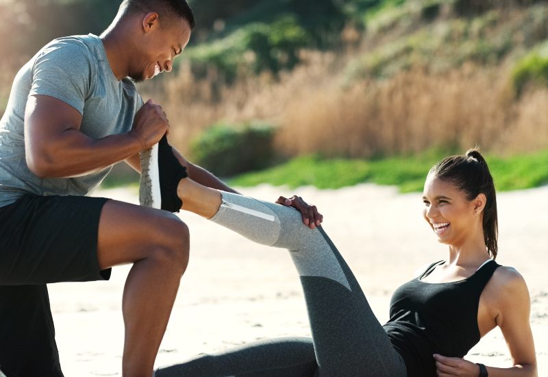 Man helping woman stretch legs before exercising in Crofton, MD