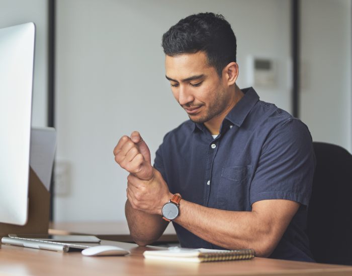 Man experiencing wrist pain while working on the computer