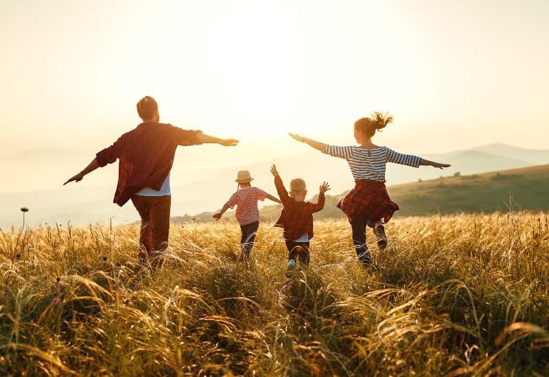 Family of four with young children running through a field during sunset in Millersville