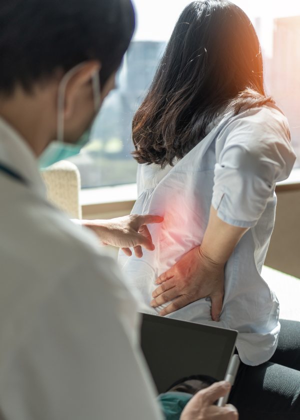 Chiropractor examining woman's lower back pain