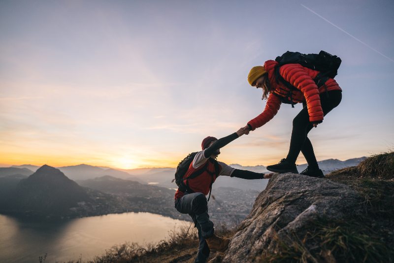 Couple hiking and climbing up a mountain ridge