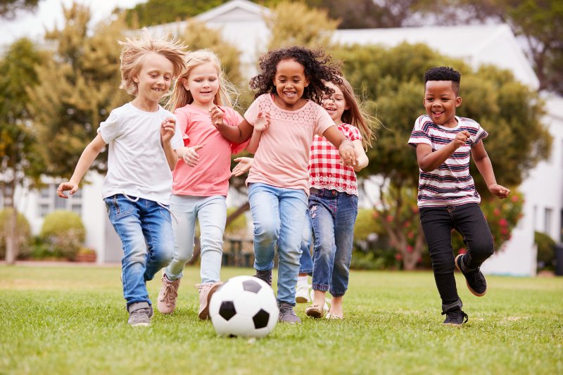 Group of young children playing soccer outside
