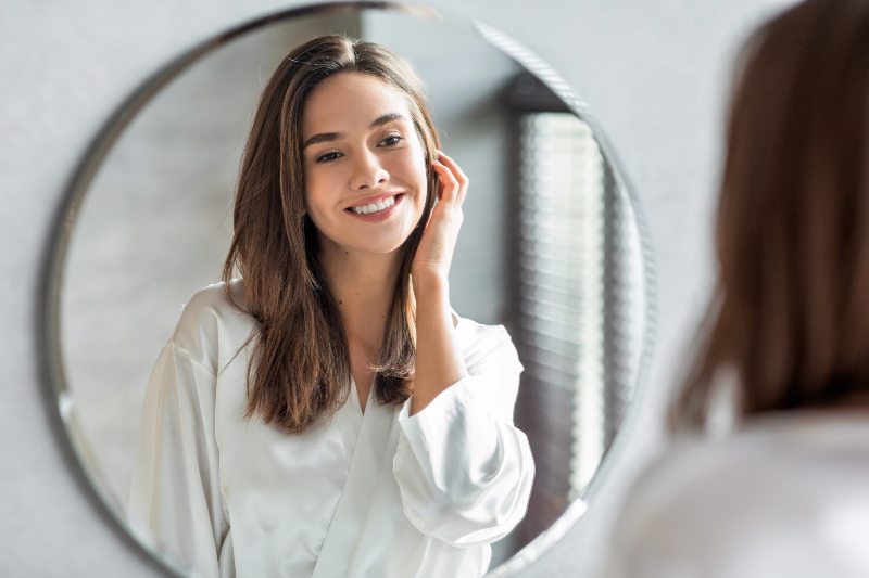 Happy woman admiring herself in bathroom mirror